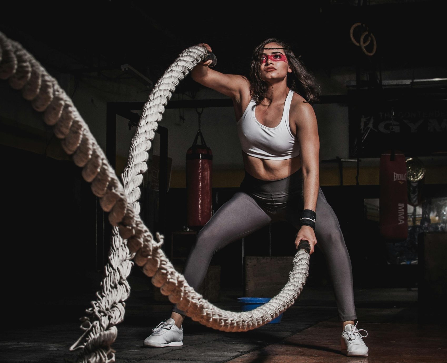 Female athlete demonstrating strength with battle ropes in a gym.