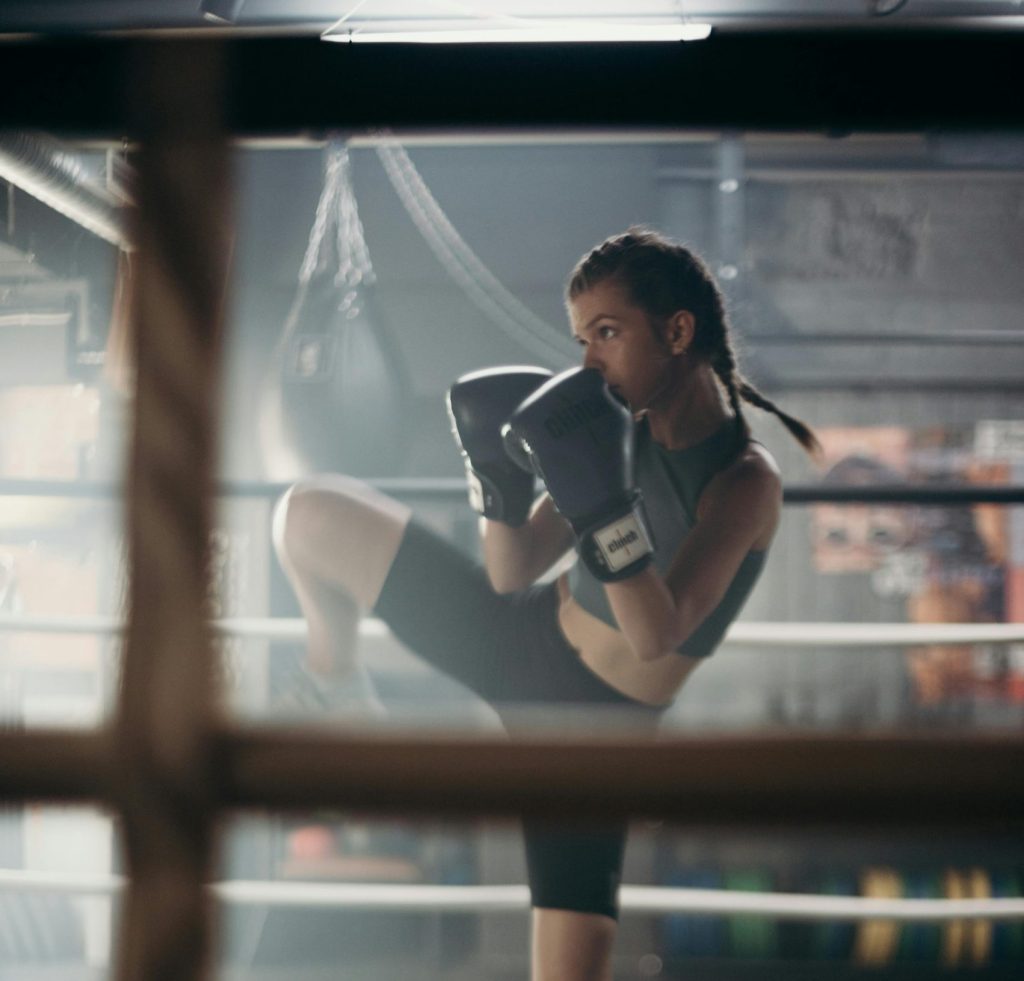 Determined young woman practicing kickboxing in a gym with focused stance.
