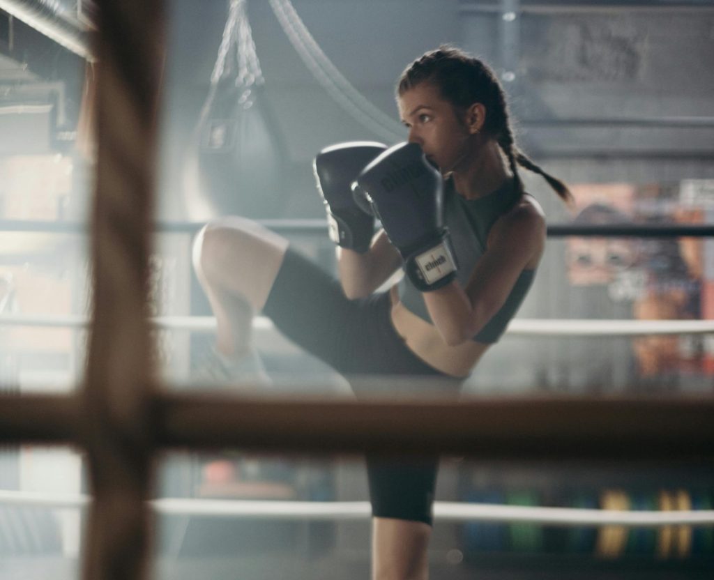Determined young woman practicing kickboxing in a gym with focused stance.